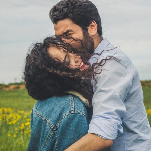 en kvinna och en man som kramar varandra på en äng